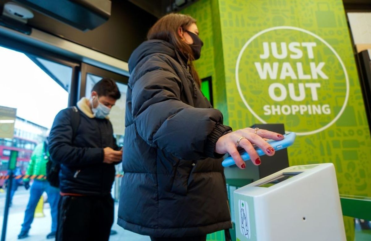 A customer scans her phone as she enters Amazon Fresh store in Ealing