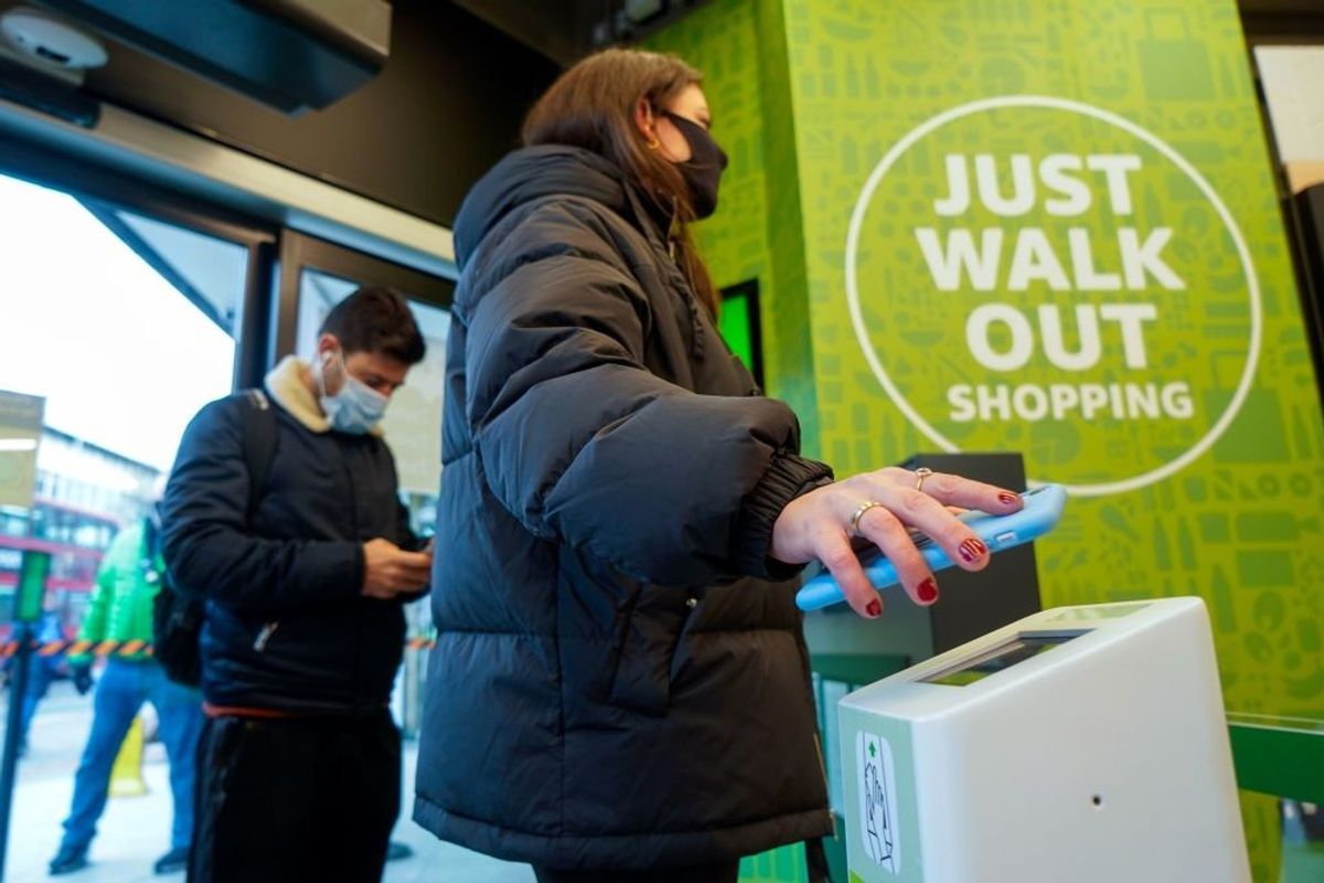 A customer scans her phone as she enters Amazon Fresh store in Ealing