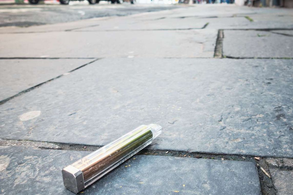 A disposable vape discarded on the pavement of a city
