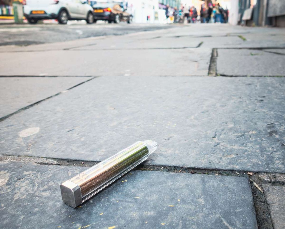 A disposable vape discarded on the pavement of a city