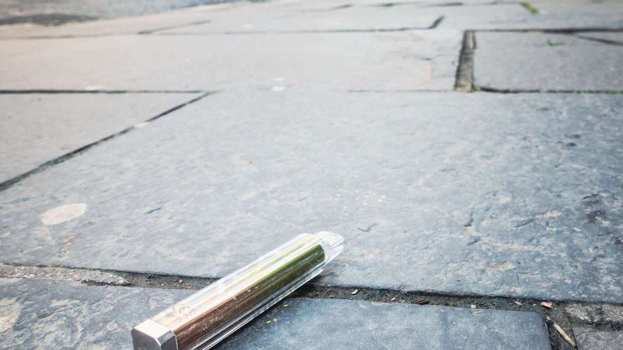 A disposable vape discarded on the pavement of a city