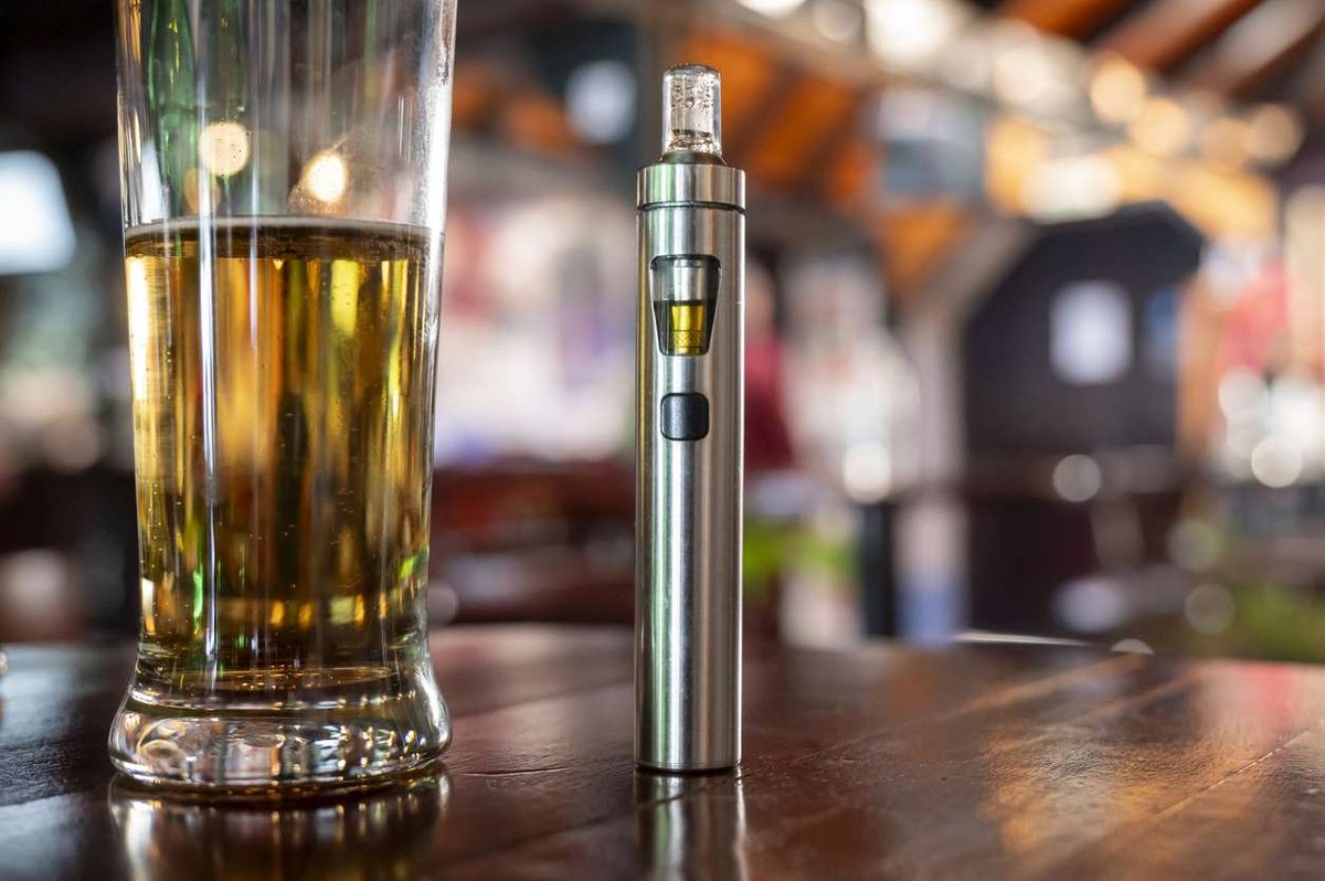 a glass of beer and a vape