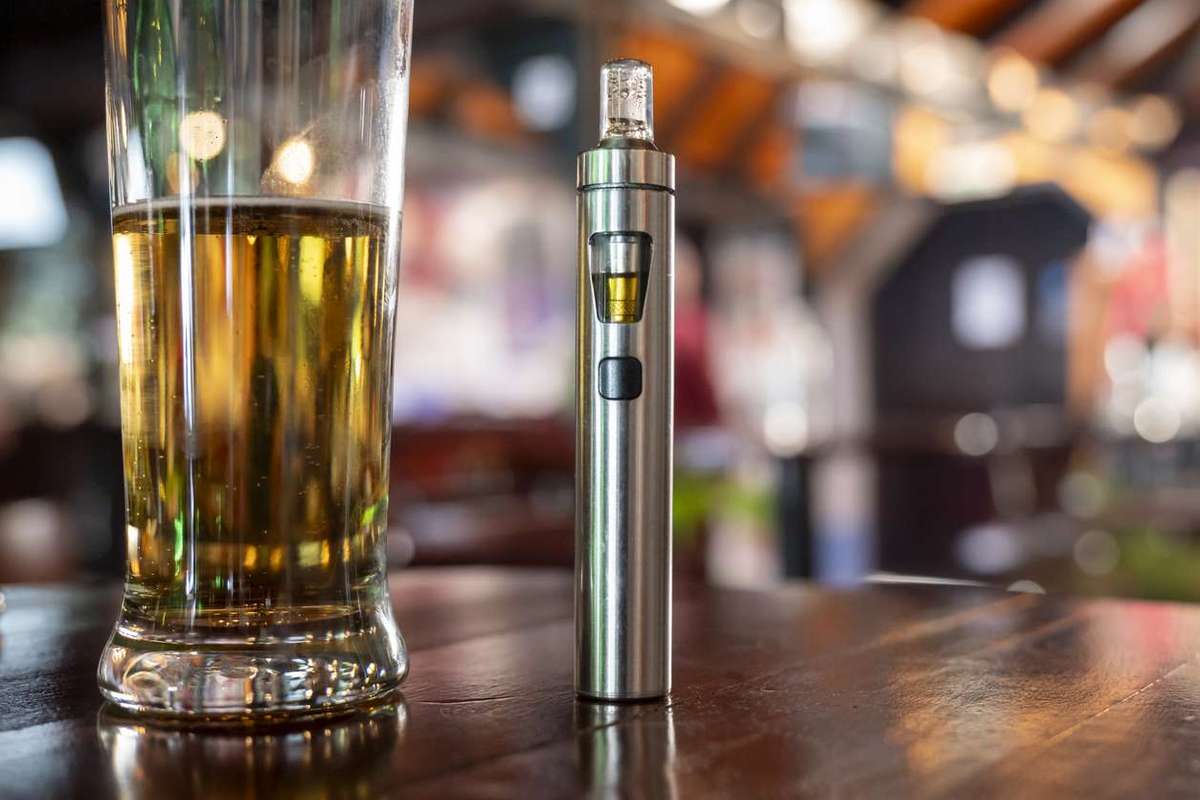 a glass of beer and a vape