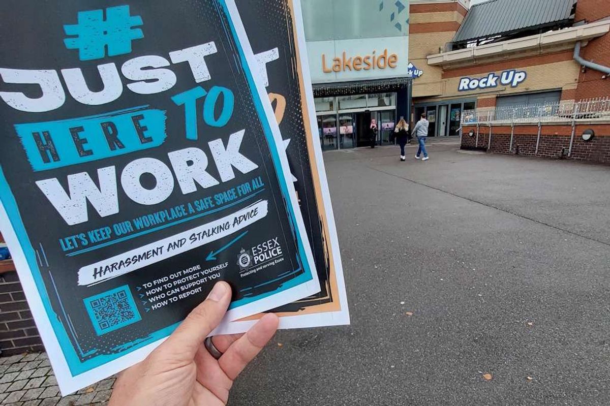 A hand holding Essex Police Just Here To Work posters at Lakeside Shopping Centre in West Thurrock, Essex