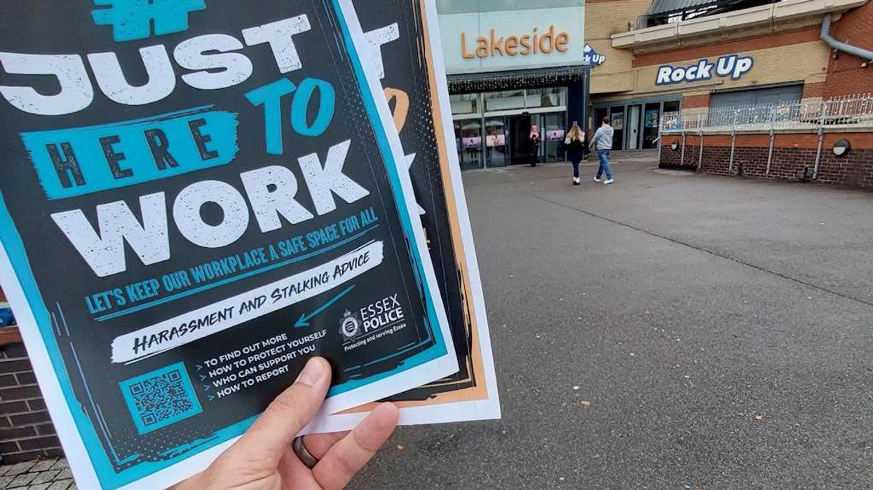 A hand holding Essex Police Just Here To Work posters at Lakeside Shopping Centre in West Thurrock, Essex
