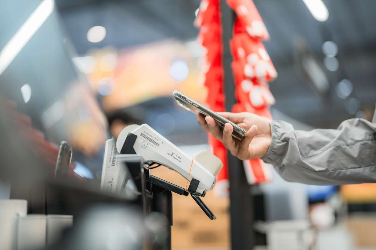 a man using his smartphone to make contactless payment at the checkout,