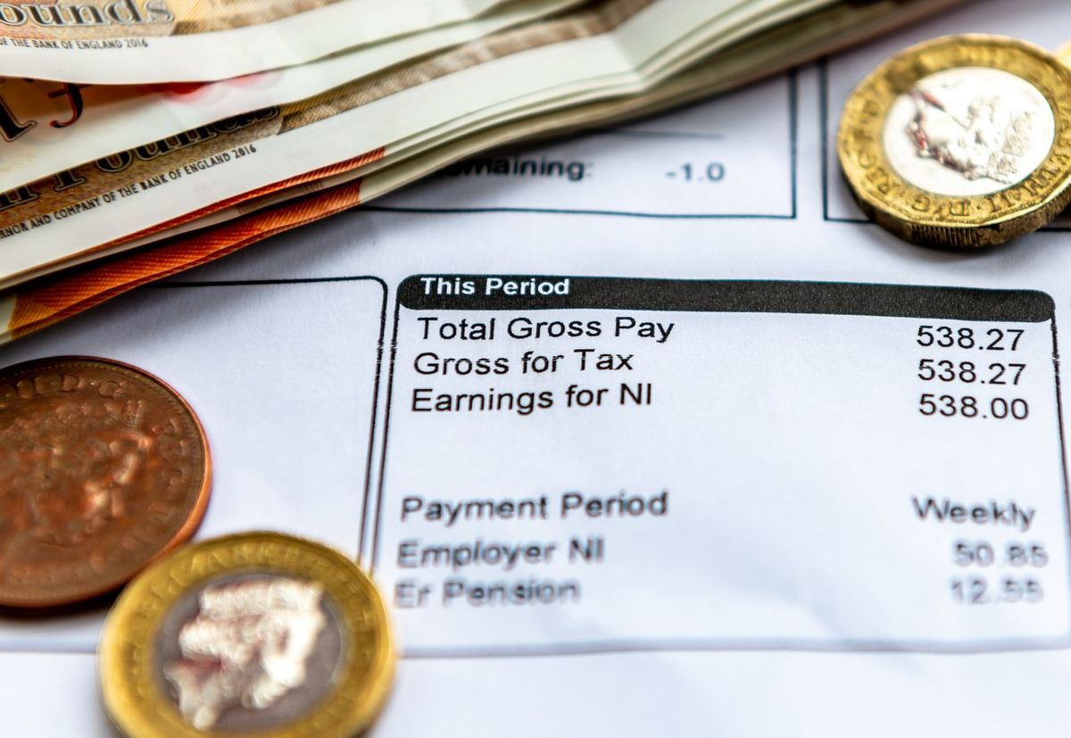 A payslip showing pay as you earn tax deductions, national insurance and pension contributions with some bank notes and coins