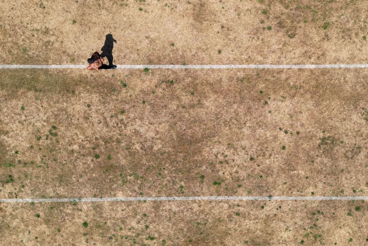 a person running along pitch markings on parched parkland