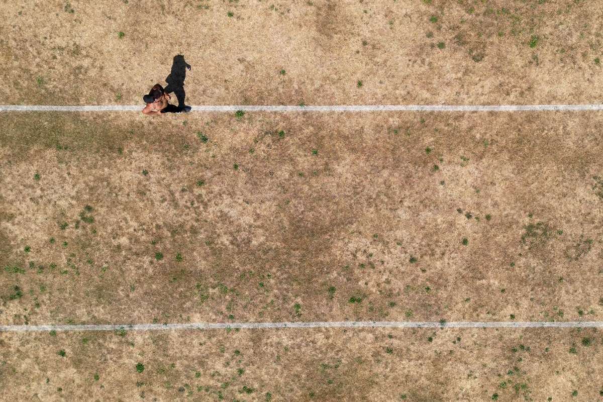 a person running along pitch markings on parched parkland