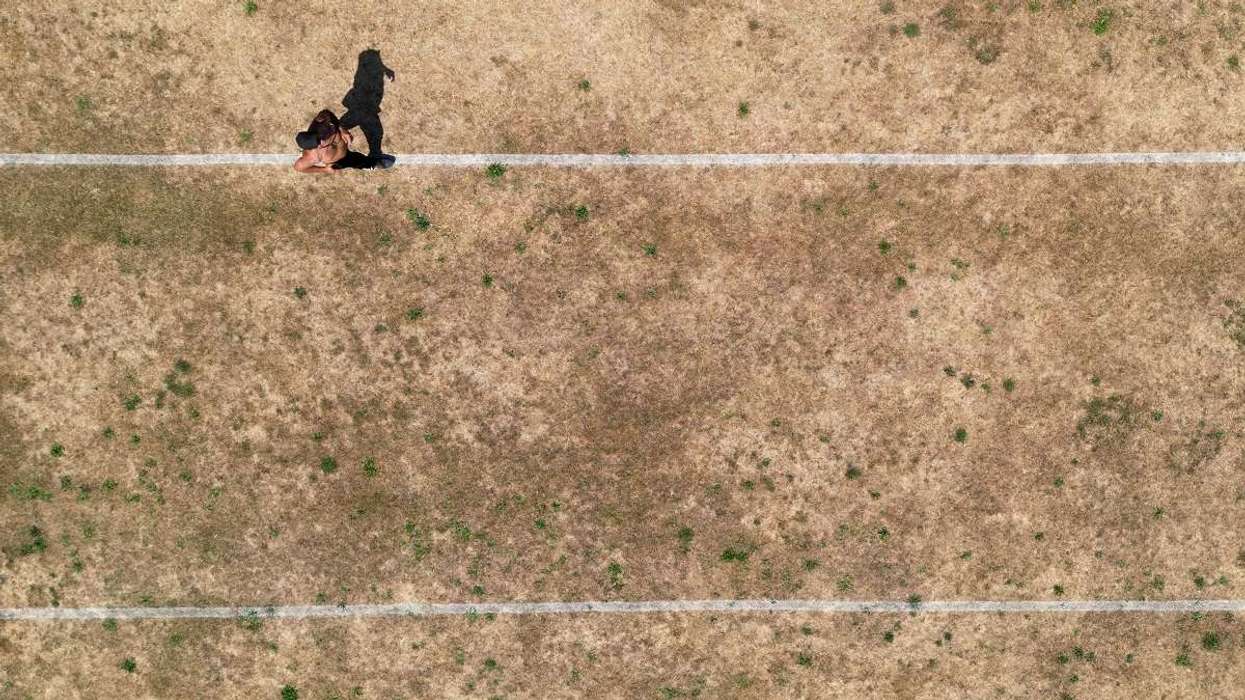 a person running along pitch markings on parched parkland