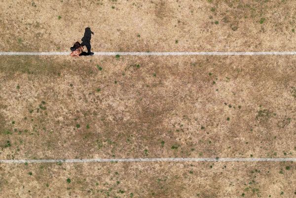 a person running along pitch markings on parched parkland