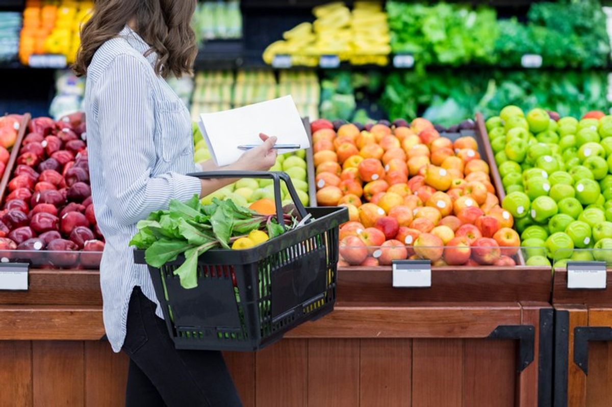 A shopper selecting fresh produce in a UK supermarket aisle.