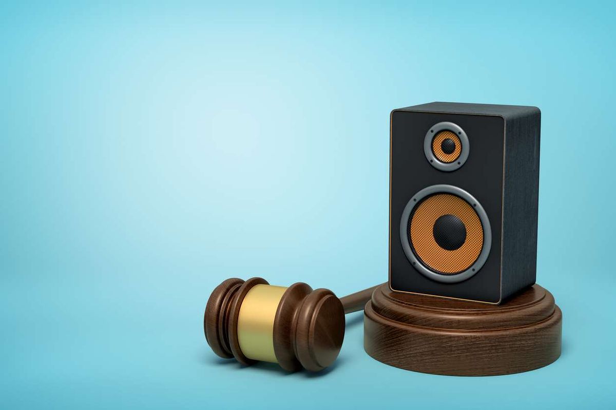 audio loudspeaker on round wooden block and brown wooden gavel 