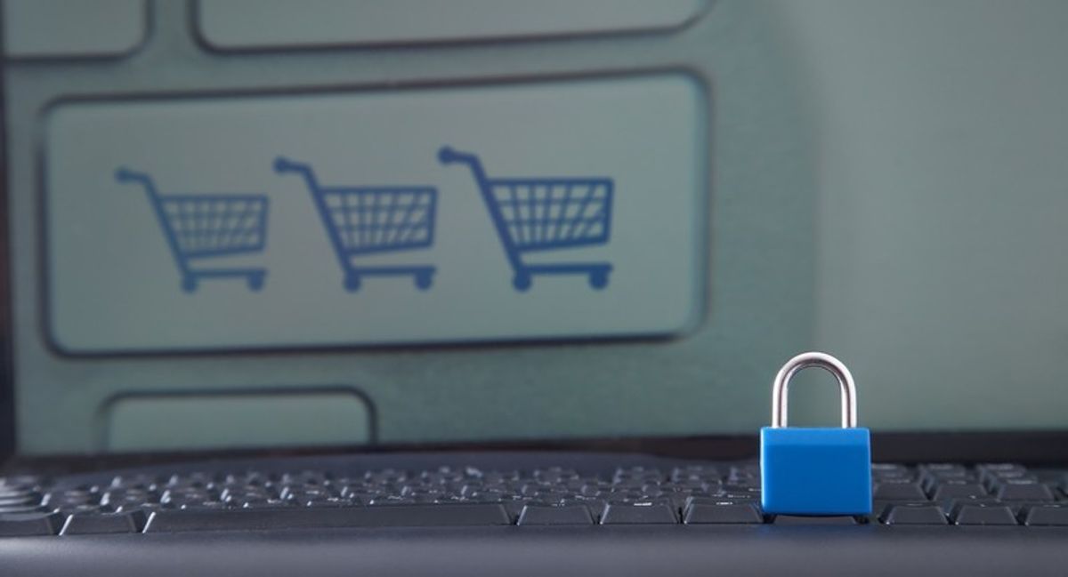 Blue padlock on keyboard with shopping cart icons on screen, symbolising cyber security in retail