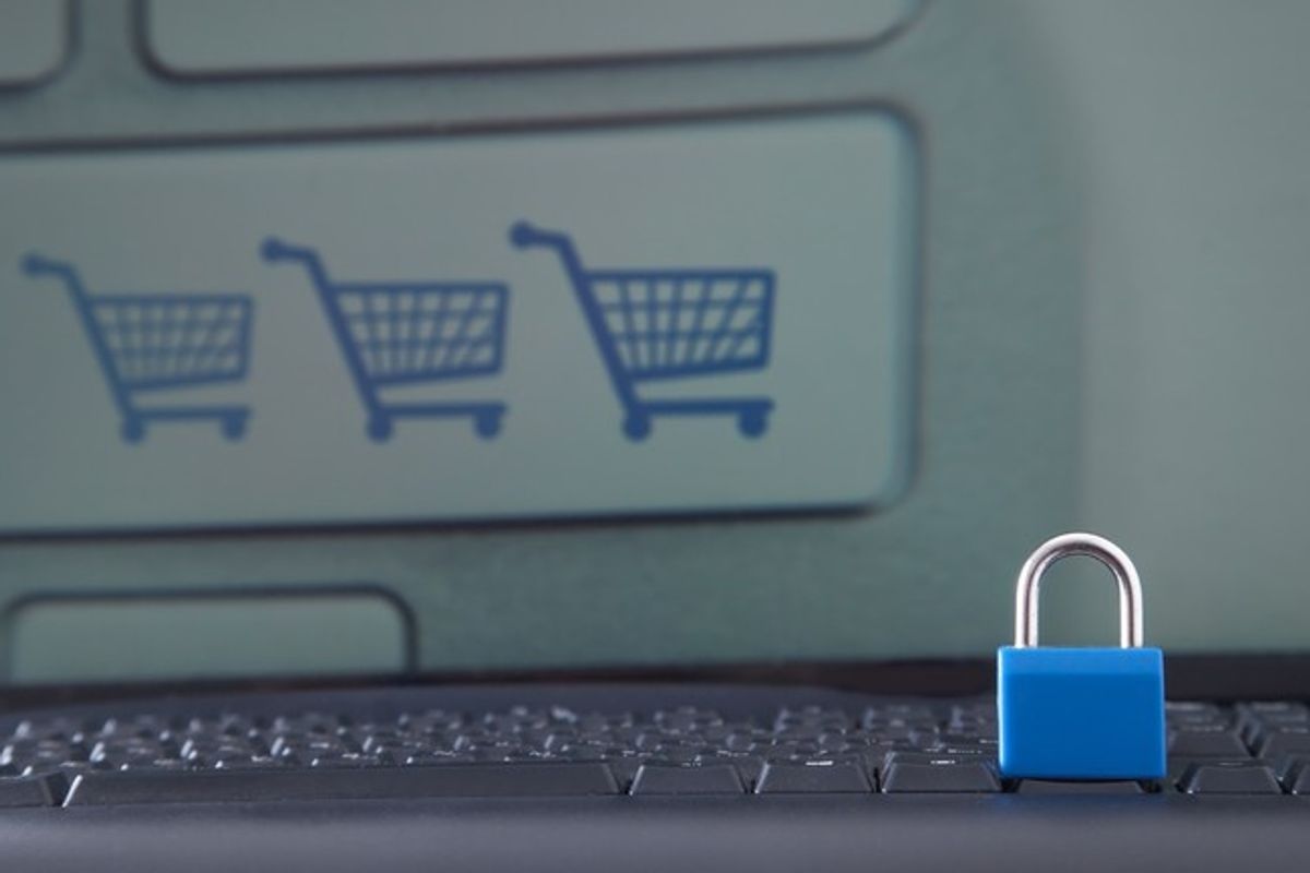 Blue padlock on keyboard with shopping cart icons on screen, symbolising cyber security in retail