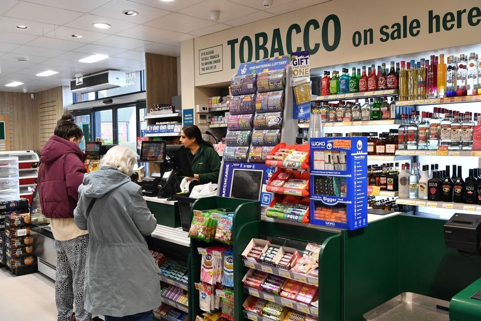 Budgens Berrymoor checkout counter in Wellingborough with customers and staff, showcasing tobacco and alcohol products