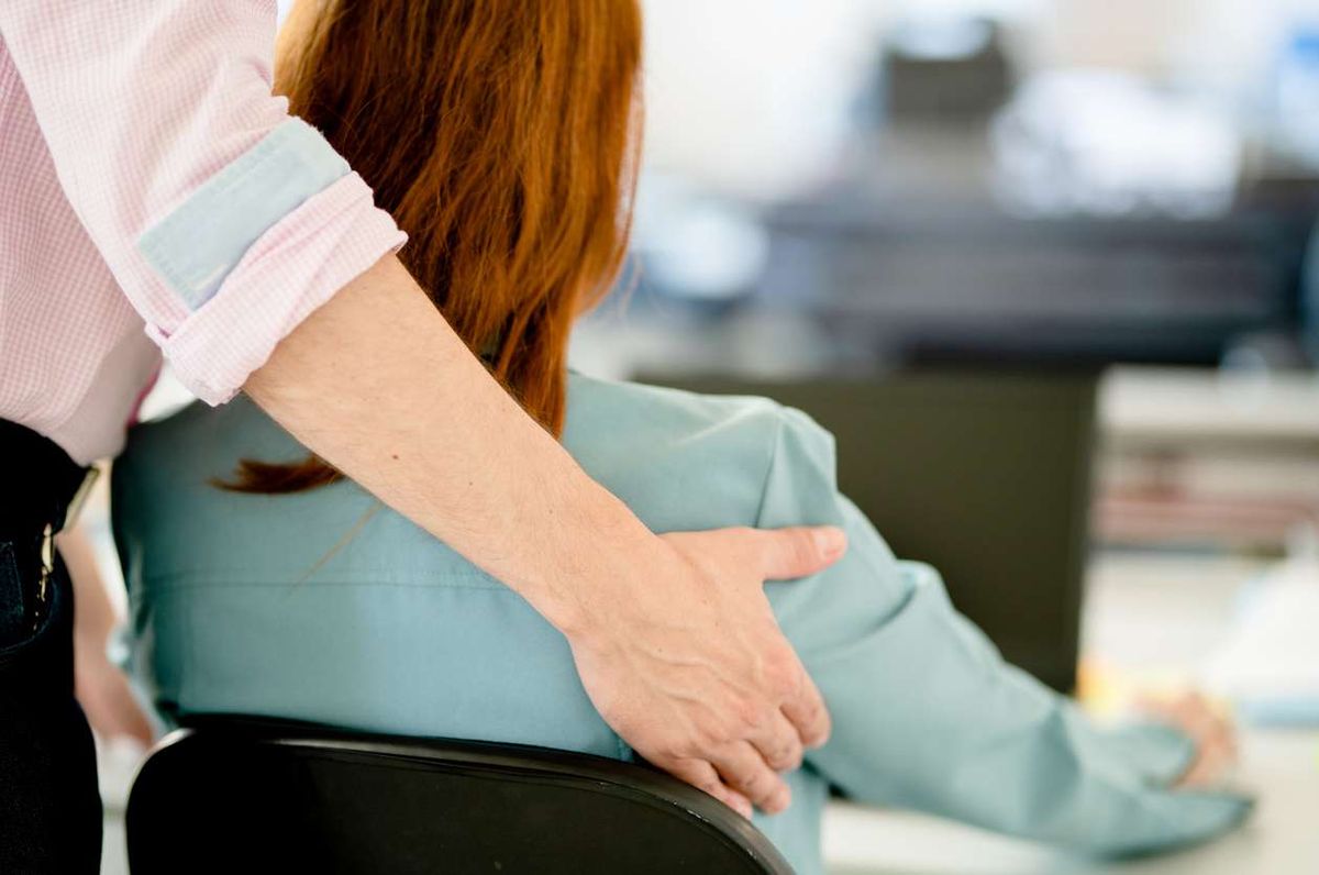 Businessman sexually harassing a female colleague in an office