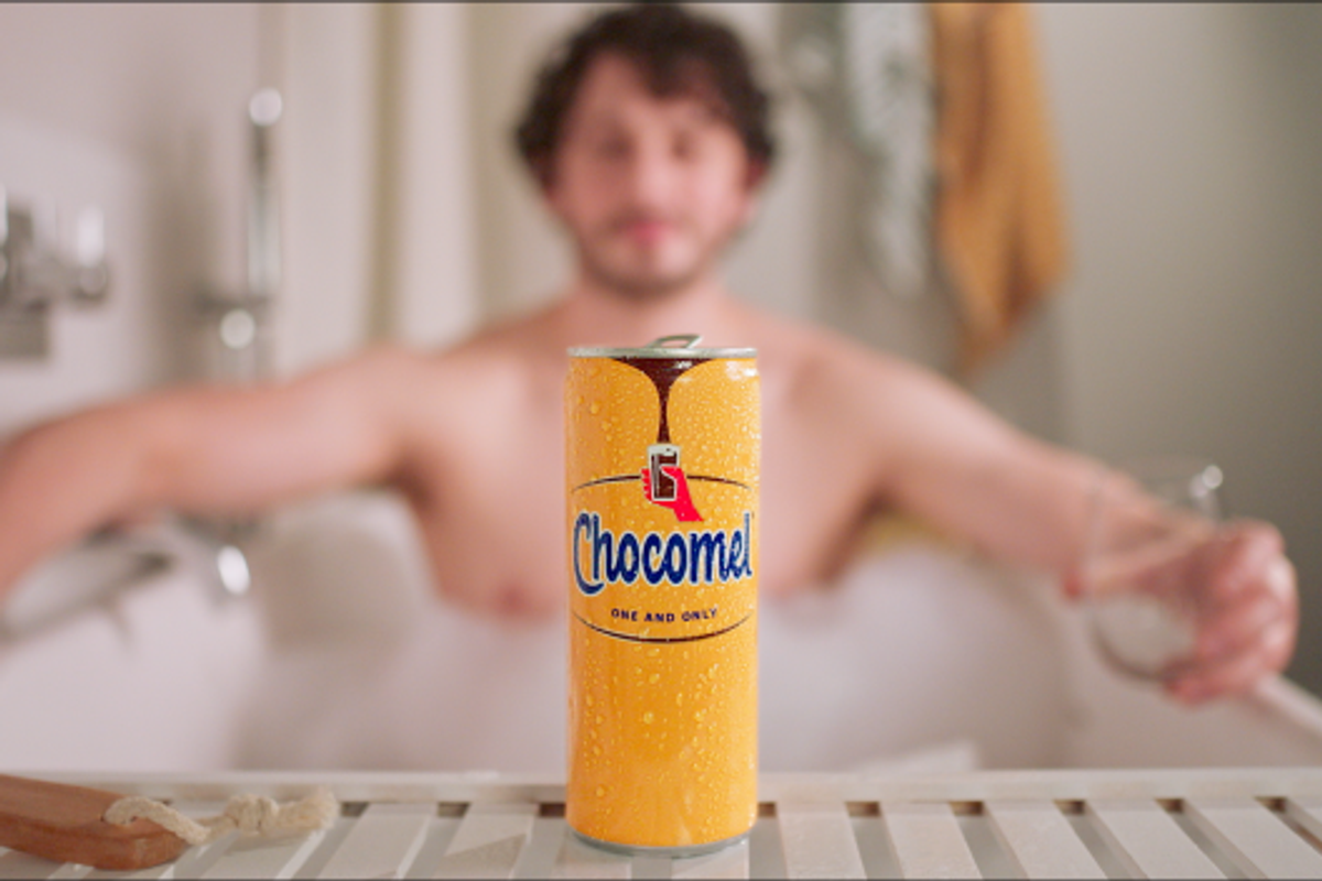Chocomel advert shows person enjoying chocolate milk alone in bathtub, smiling.