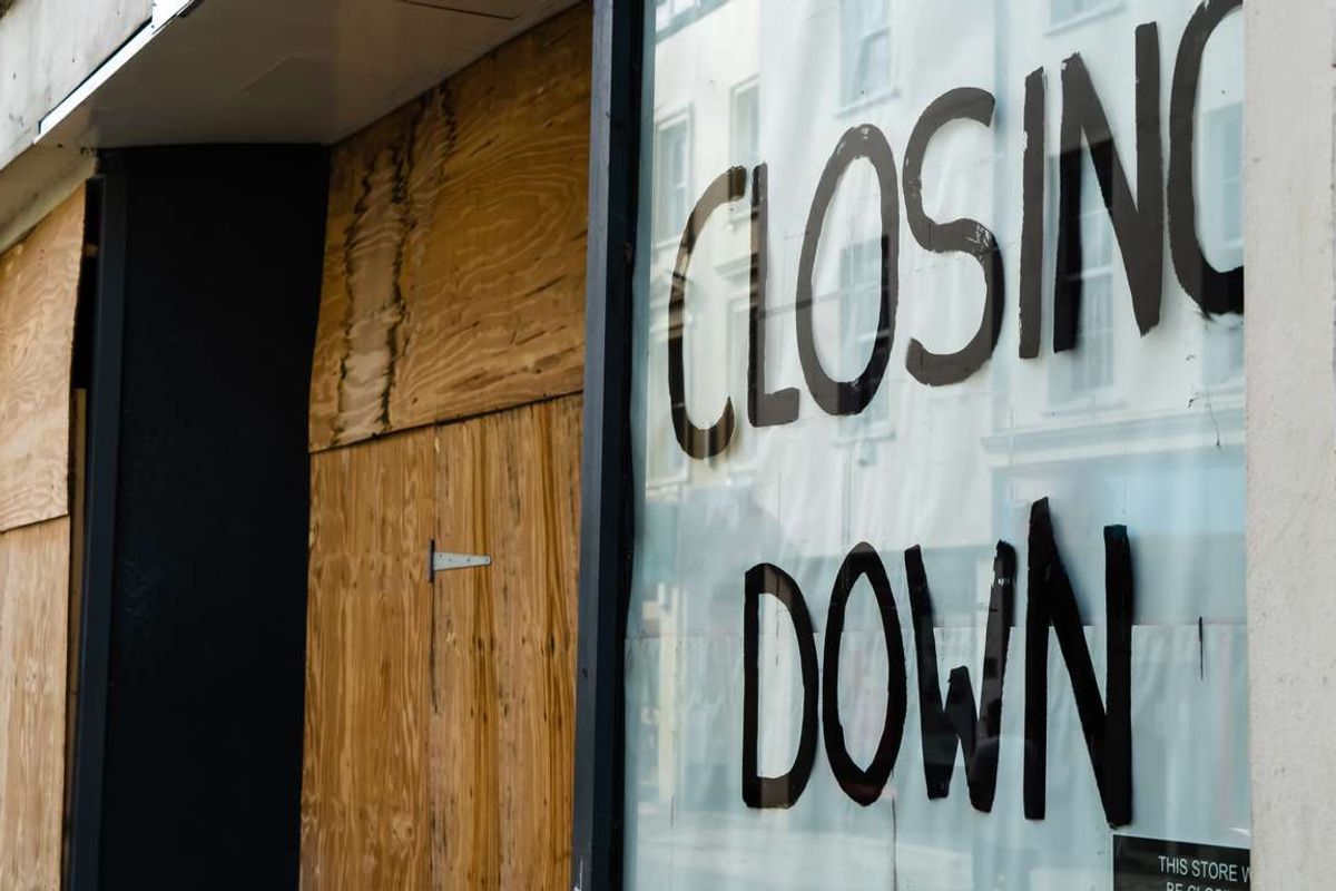 Closing down sign in a boarded-up shop window