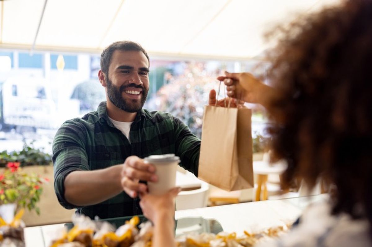 Customer receiving to-go coffee and bag at food-to-go convenience stores 2025