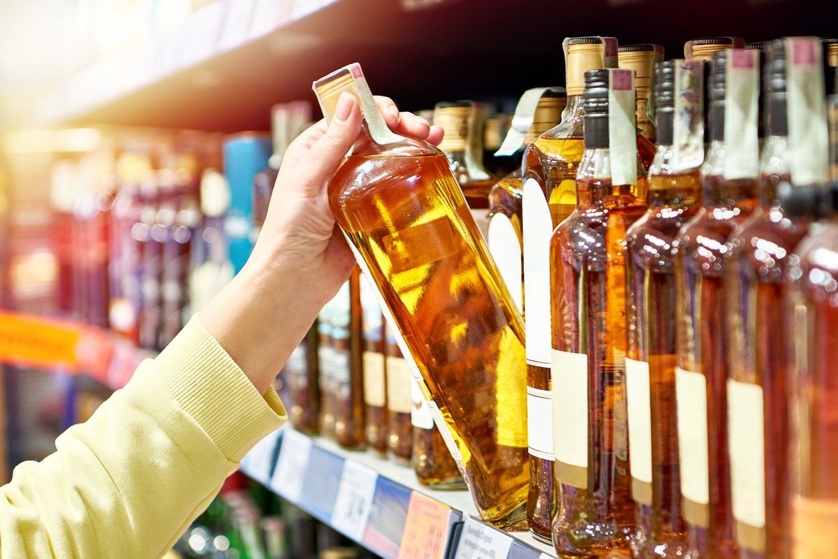 Customer selecting spirits in convenience store per Nick Gillett’s 2025 guide