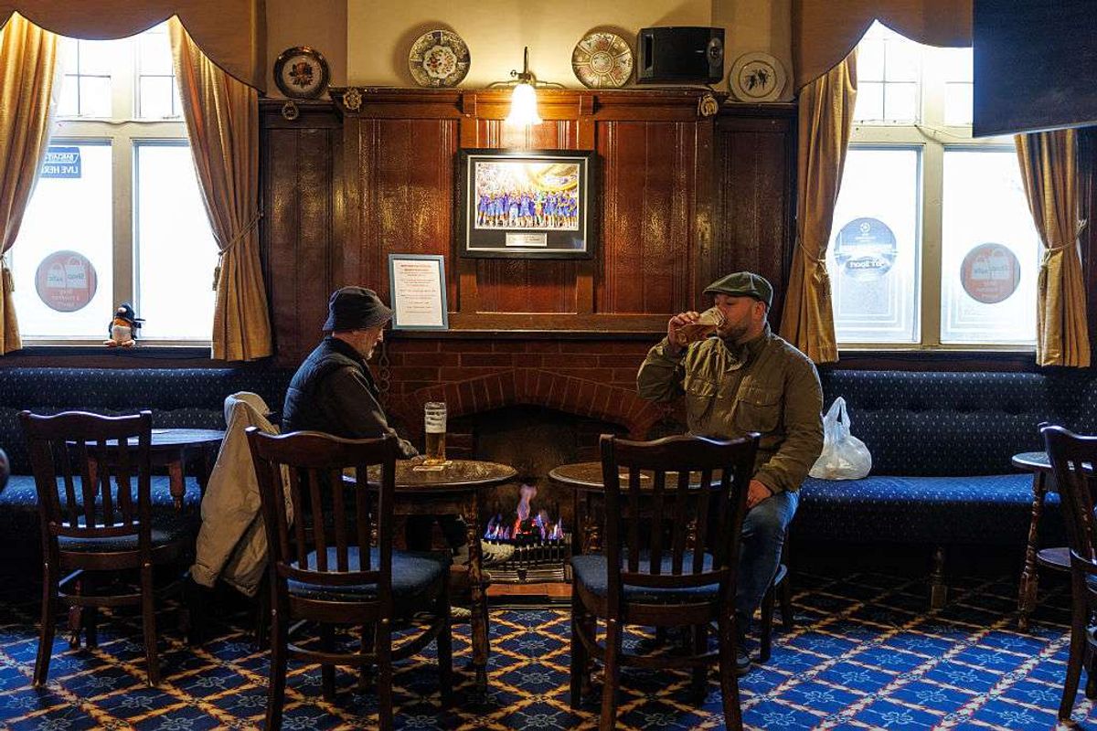 Customers talk and enjoy a drink in front of an open fire at the Dukes Head pub in Crayford