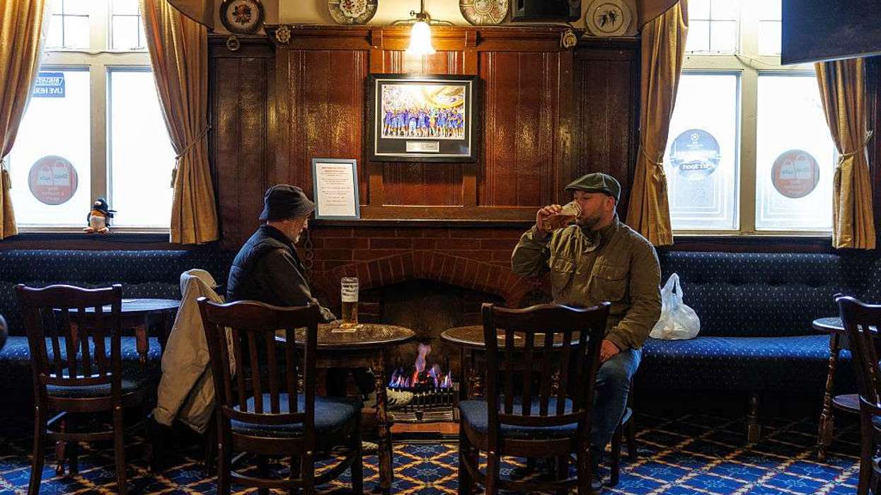 Customers talk and enjoy a drink in front of an open fire at the Dukes Head pub in Crayford
