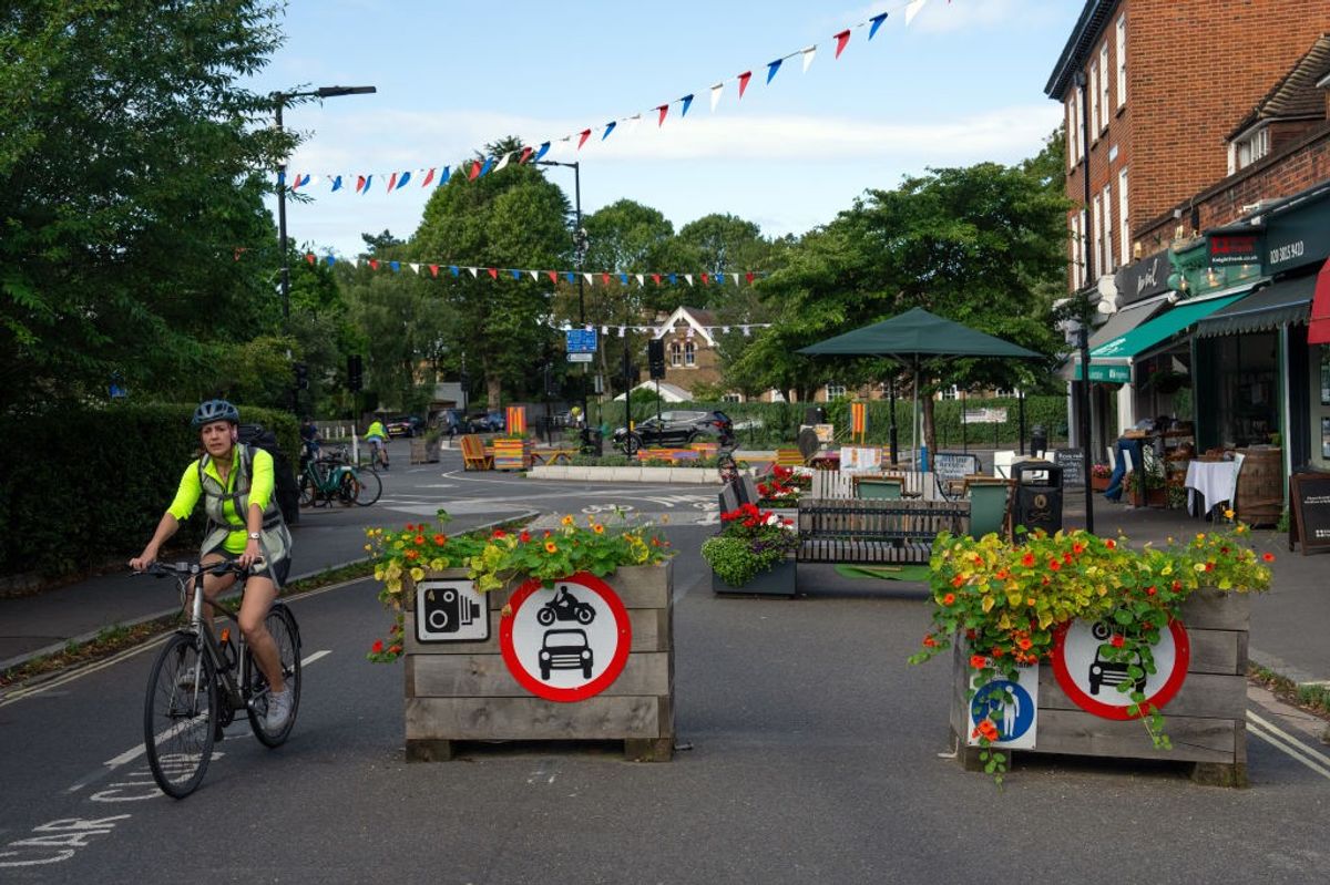 Cyclist on a Low Traffic Neighbourhood street with planters and no-car signs, enhancing UK high streets for retailers and traders