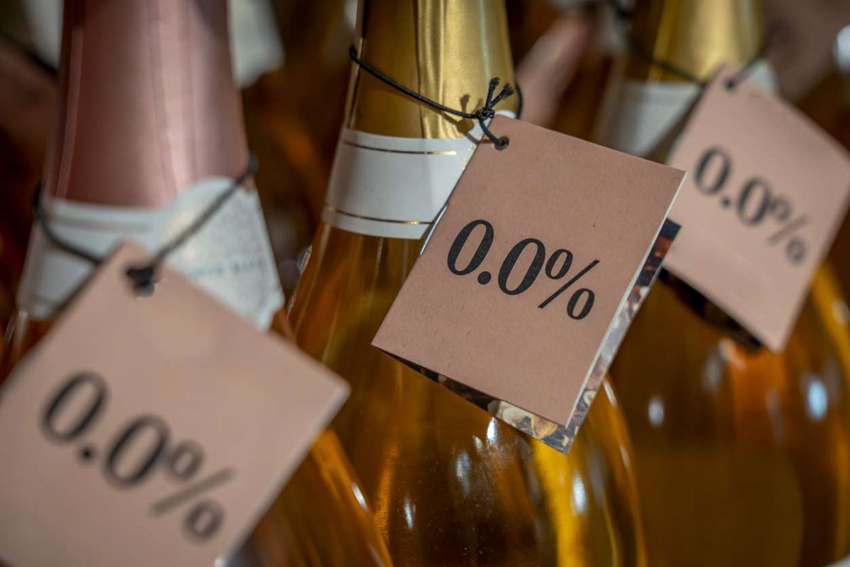 Detail of the neck of three bottles of white wine with a 0.0% alcohol-free label in a store