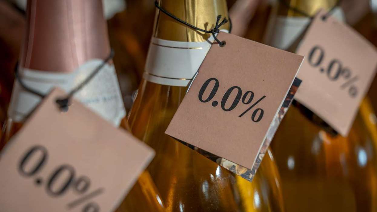 Detail of the neck of three bottles of white wine with a 0.0% alcohol-free label in a store