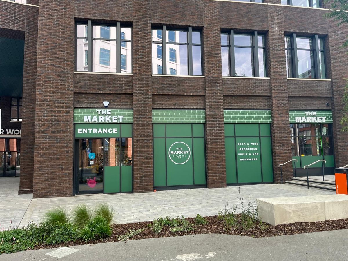Exterior view of The Market convenience store at Sugar House Island, Stratford, welcoming shoppers.