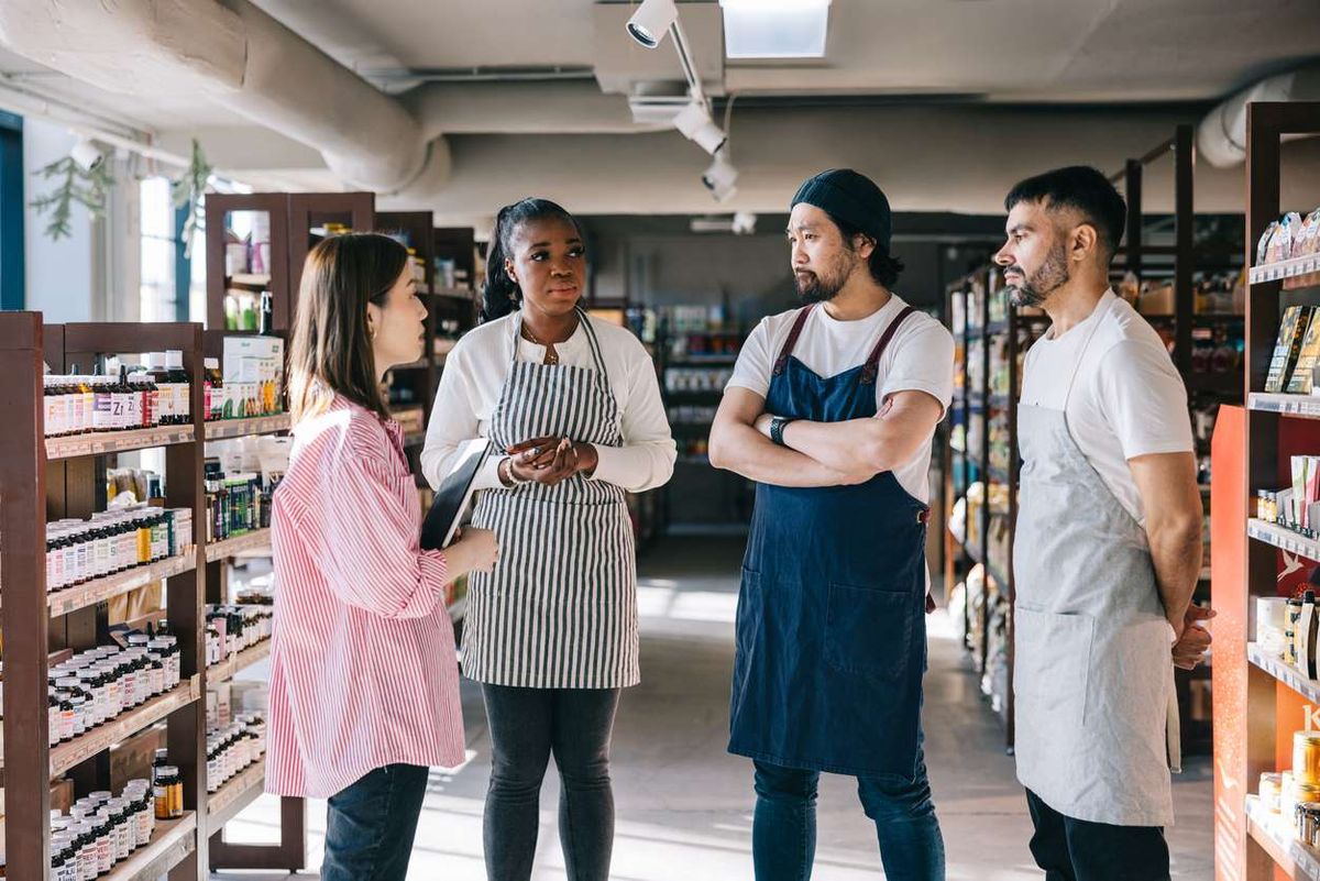 female shop manager having a chat with her employees at a convenience store
