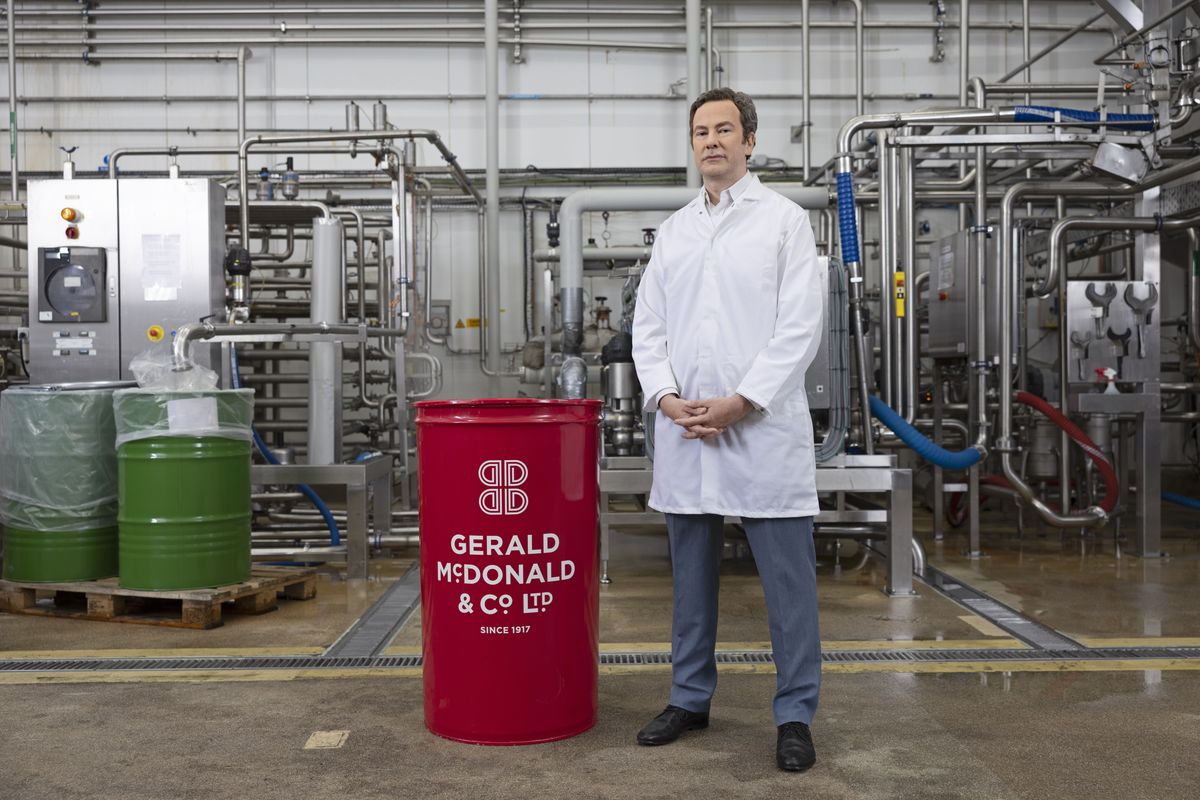 Gerald McDonald factory worker stands beside branded red drum in production facility