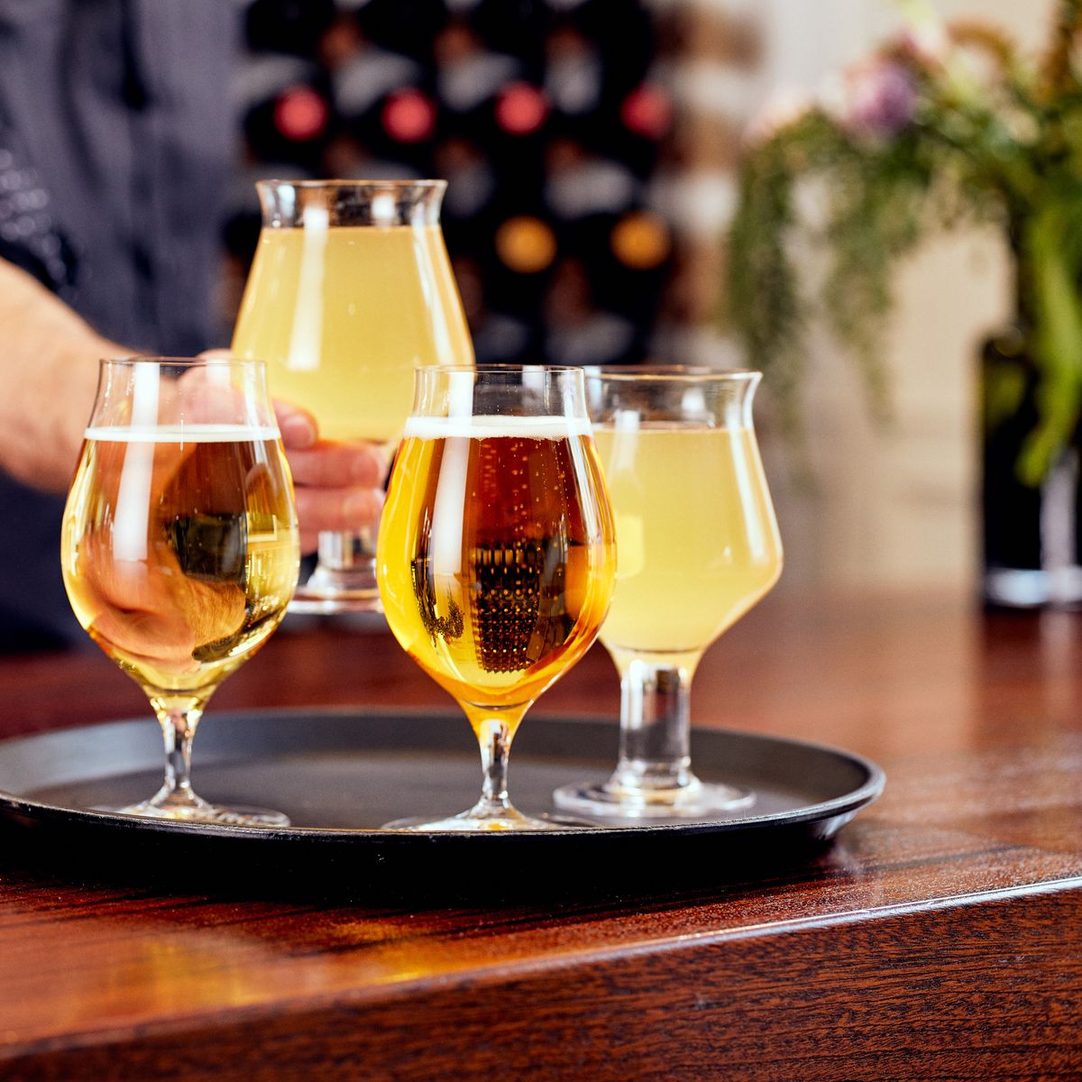Glasses of chilled cider on a tray in a bar setting, ready to be served during summer season