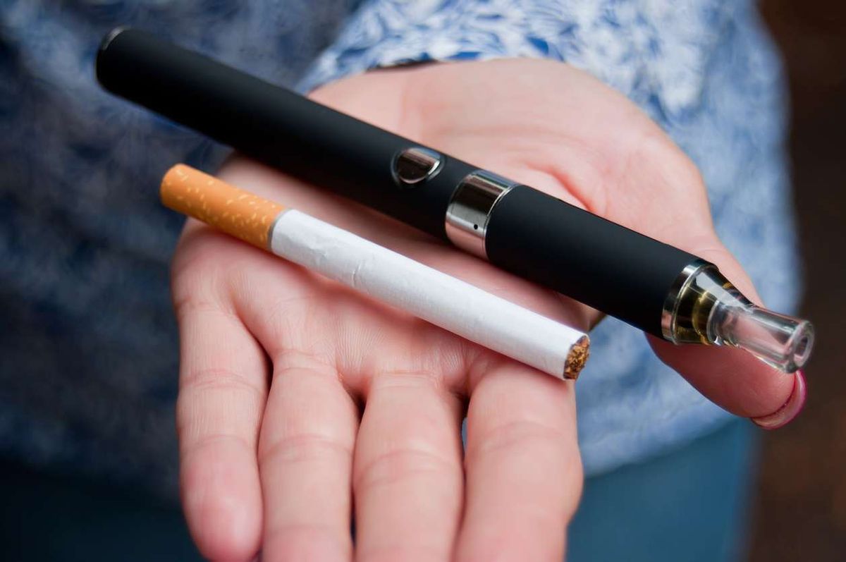 Hand of woman with an e-cigarette and a cigarette