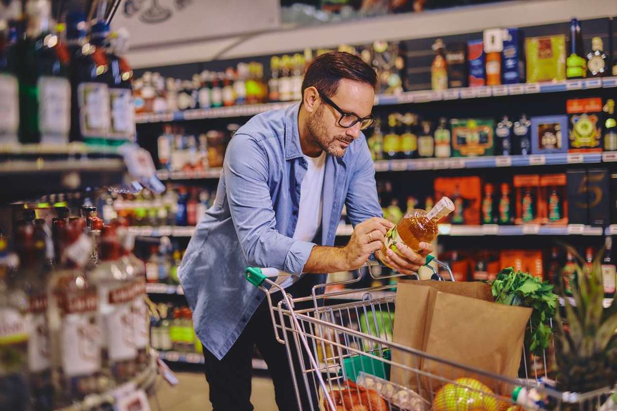 Man at the supermarket looking at an alcohol bottle