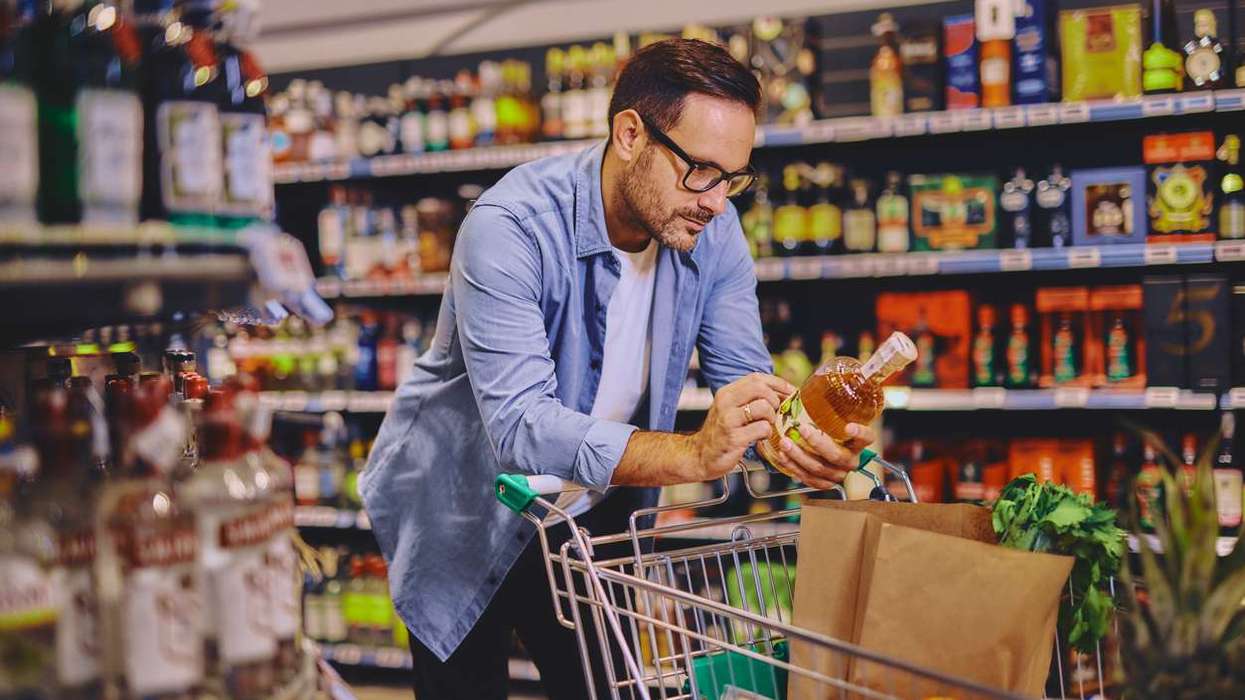 Man at the supermarket looking at an alcohol bottle