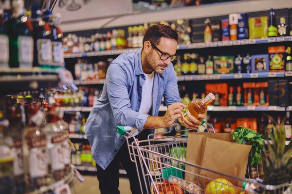 Man at the supermarket looking at an alcohol bottle