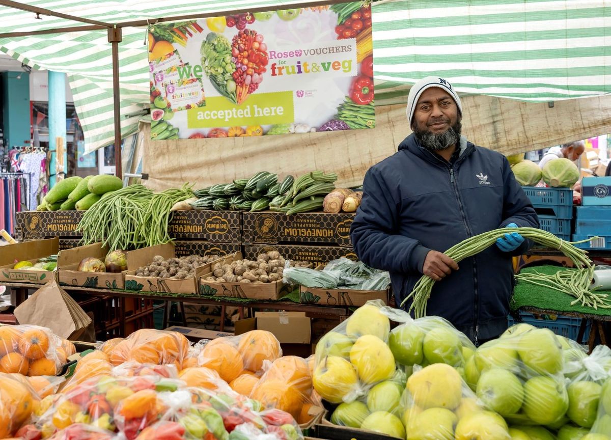 Market trader with Rose Vouchers fruit & veg stall in Tower Hamlets