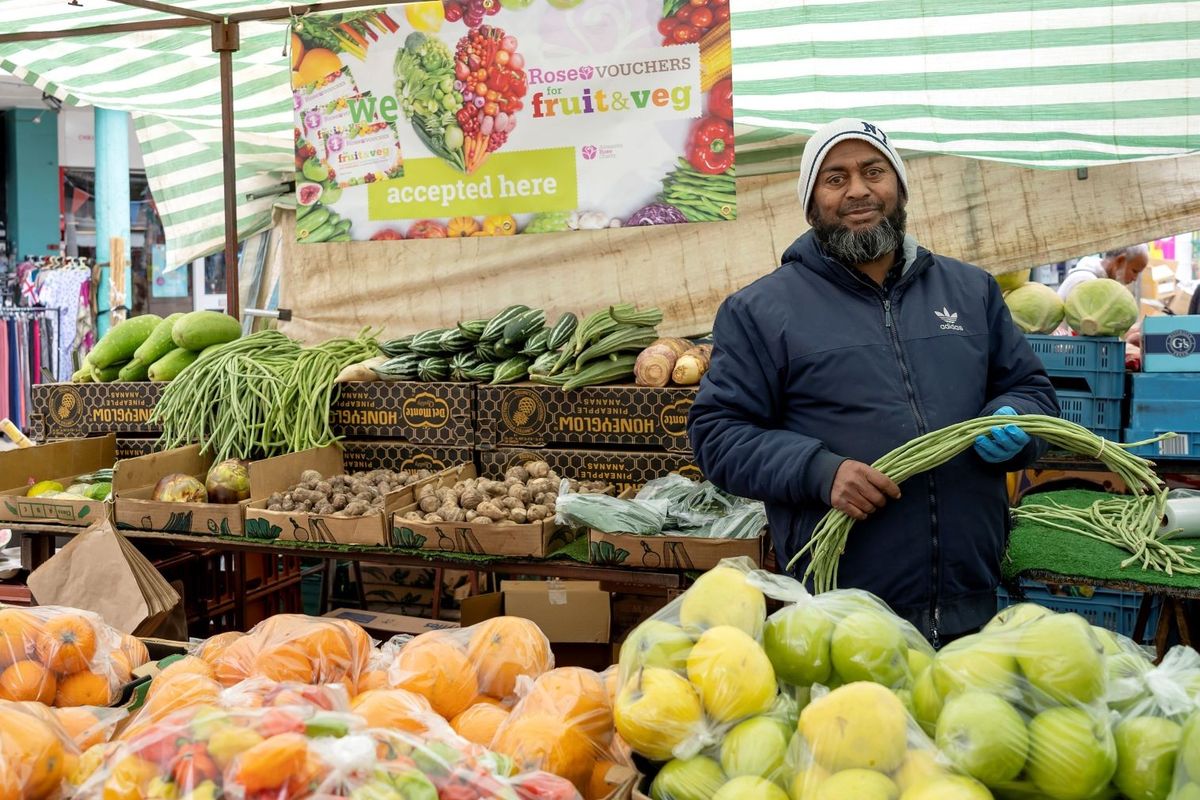 Market trader with Rose Vouchers fruit & veg stall in Tower Hamlets