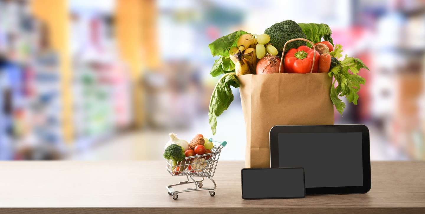 Online grocery shopping background with devices and shopping bag in supermarket