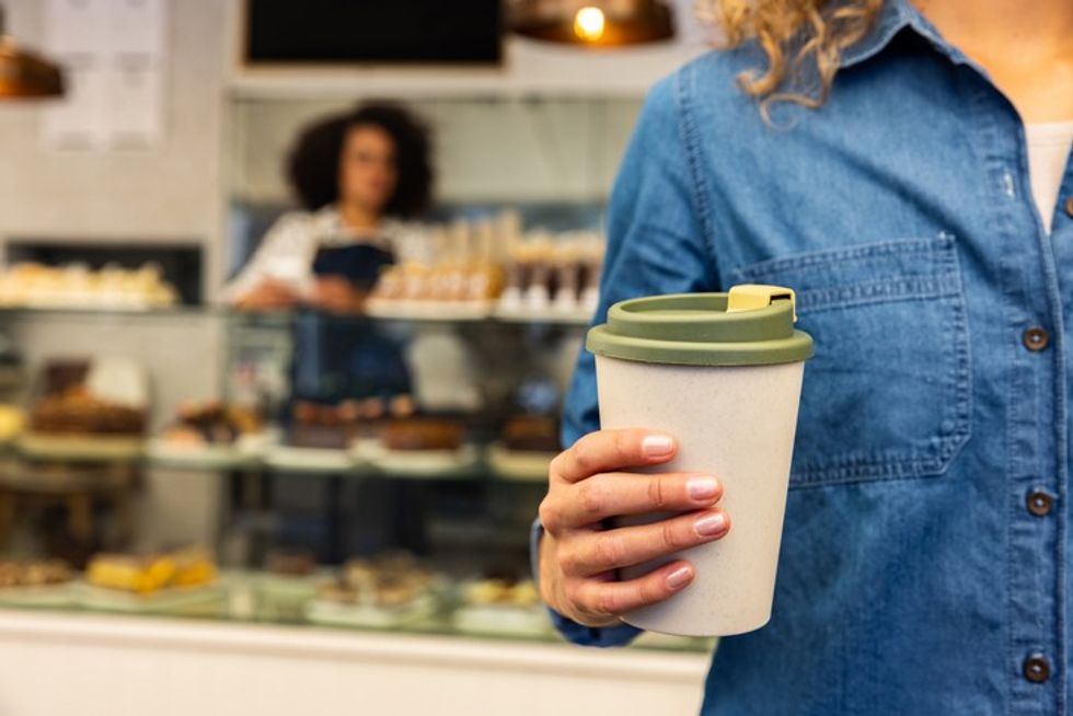 Person holding to-go coffee cup in food-to-go convenience stores 2025