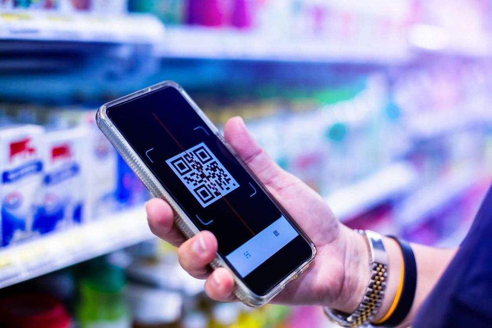 QR code tag on smartphone with blurry products on shelves in supermarkets