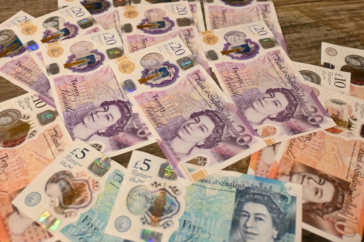 Retail cashier using Volumatic CounterCache intelligent (CCi) device for secure cash handling at the point of sale in a UK store.