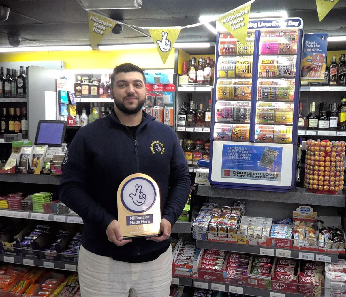 Retailer holds 'Millionaire Made Here' award in lottery ticket store
