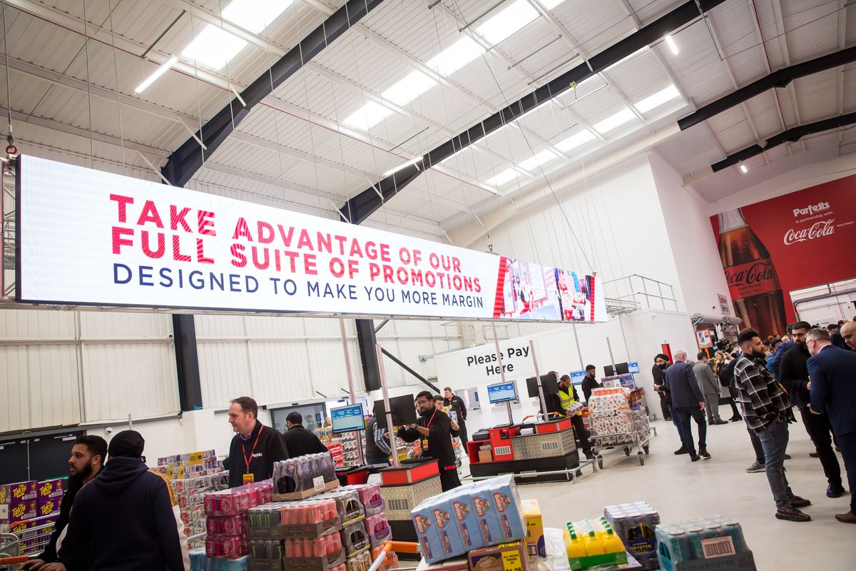 Retailers browse Parfetts depot under banner promoting profit-boosting trade promotions.