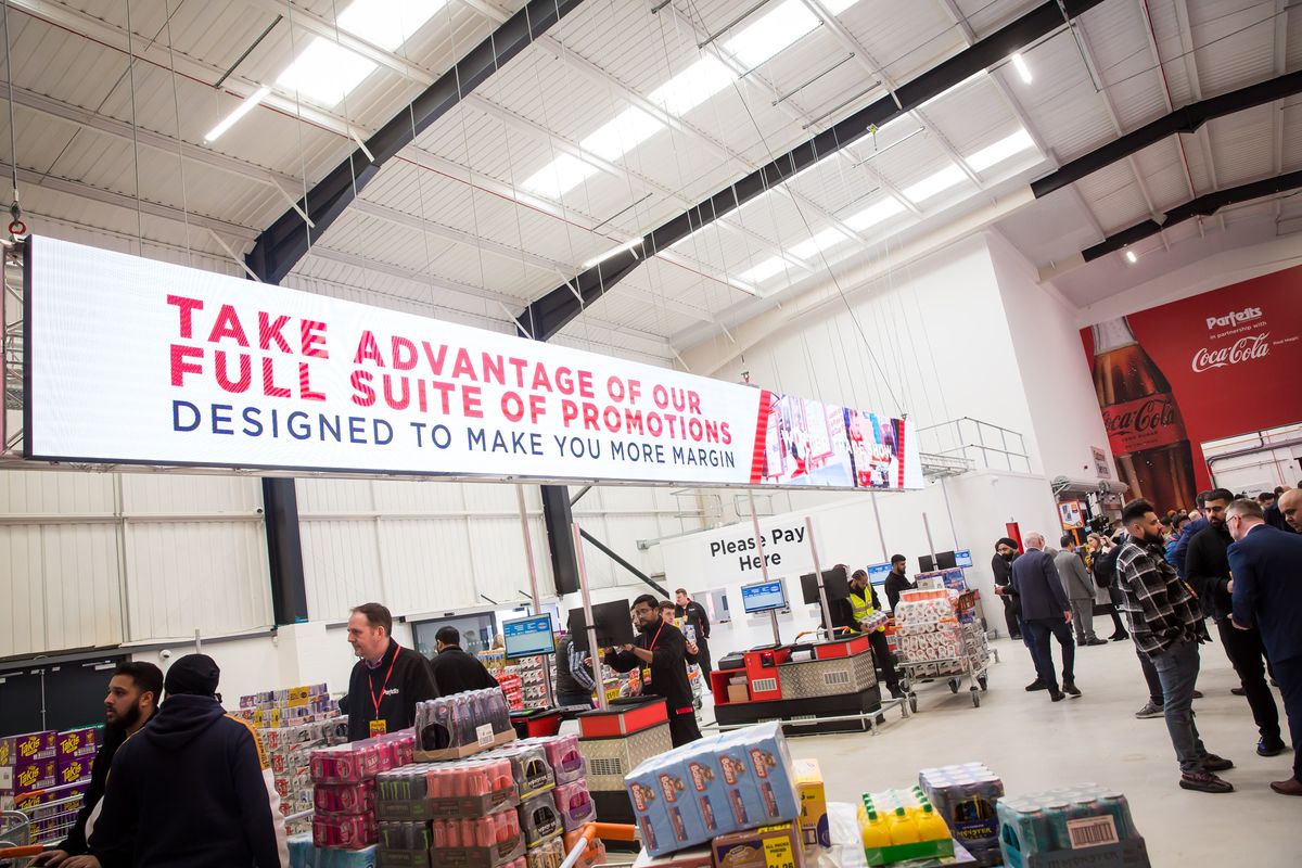 Retailers browse Parfetts depot under banner promoting profit-boosting trade promotions.