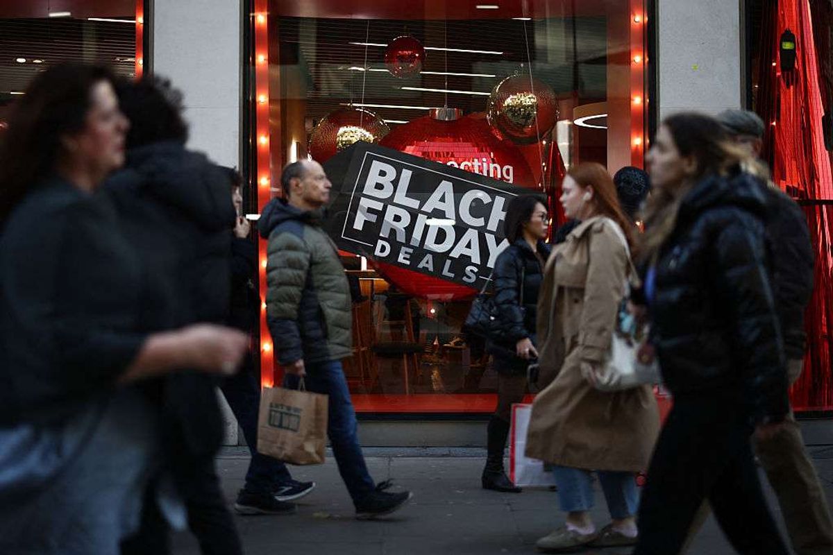 Shoppers pass window displays advertising Black Friday discounted sales