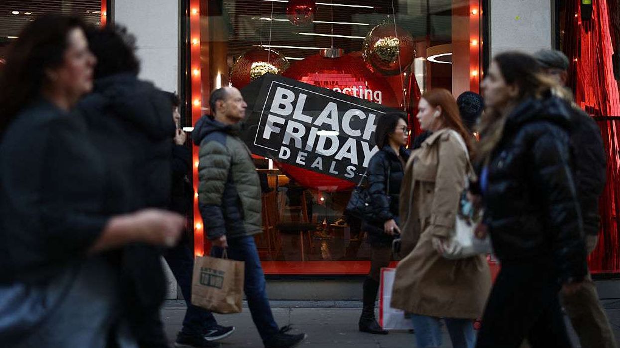 Shoppers pass window displays advertising Black Friday discounted sales