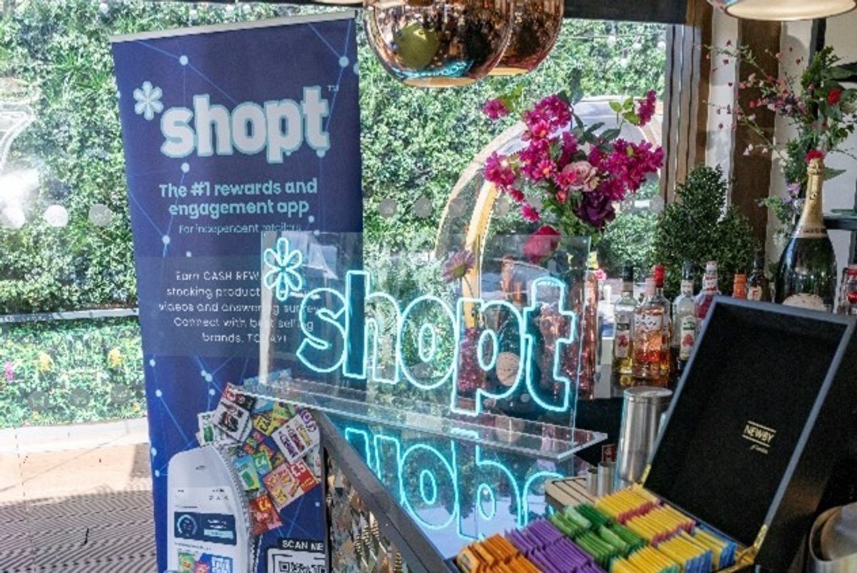 Shopt summer event display with neon logo, drinks, and flowers